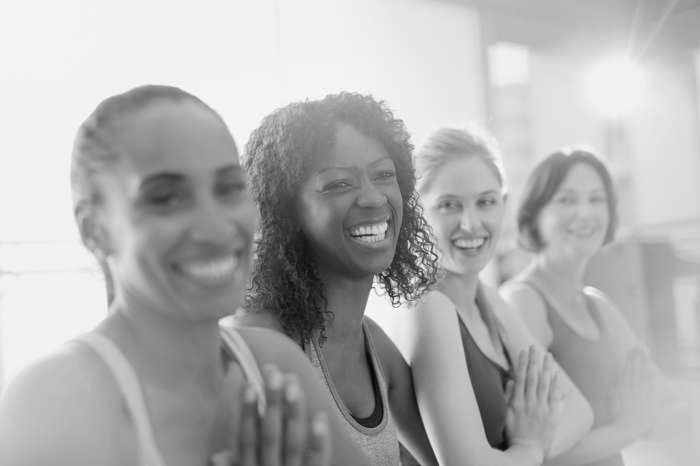 Four people smiling side by side in a fitness class