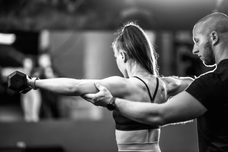 A coach guiding a member through a dumbbell movement