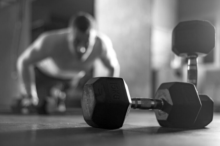 Dumbbells on the floor with a member training behind them
